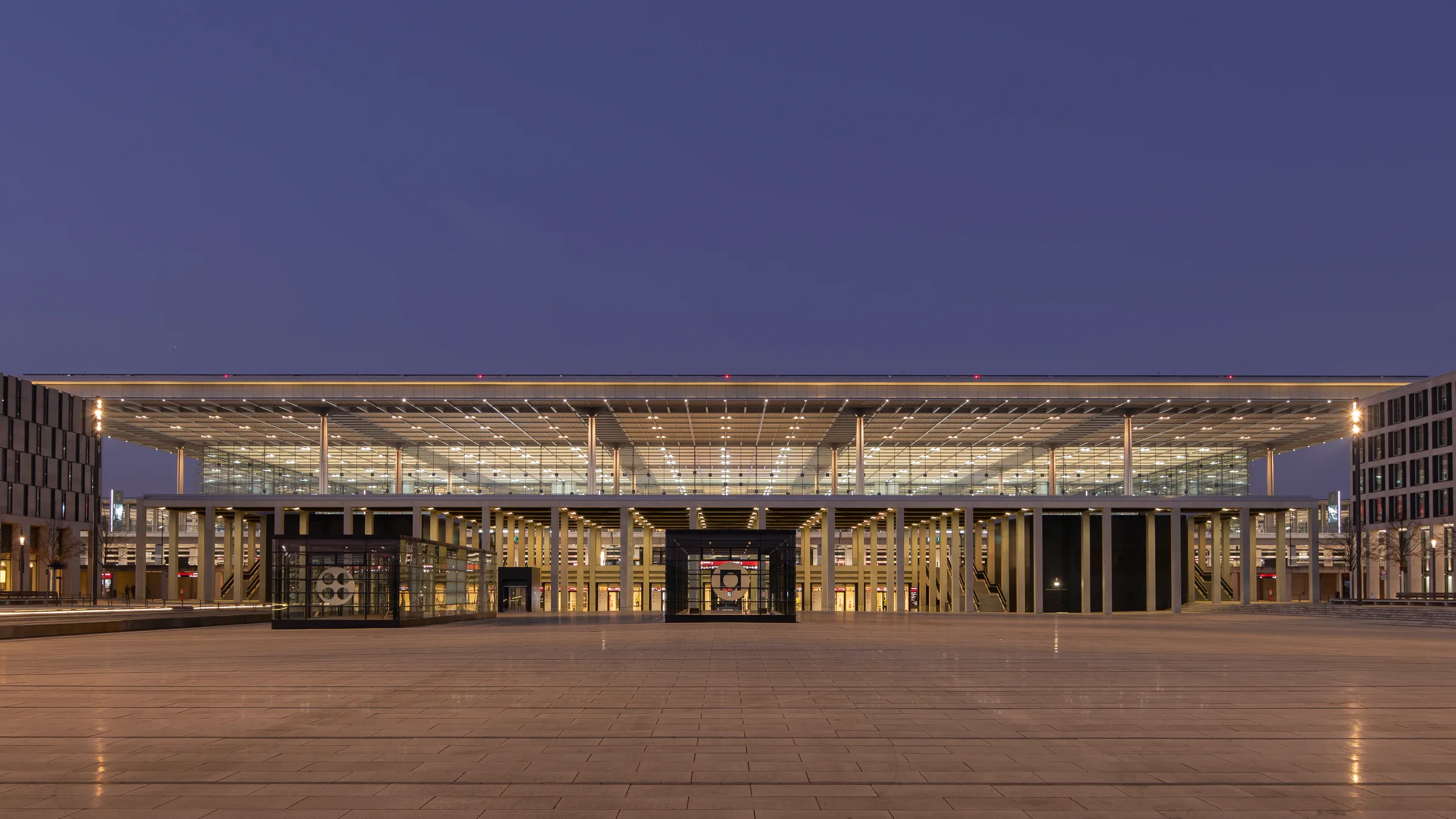 The terminal at Berlin Brandenburg Airport lit at night beneath a deep blue sky
