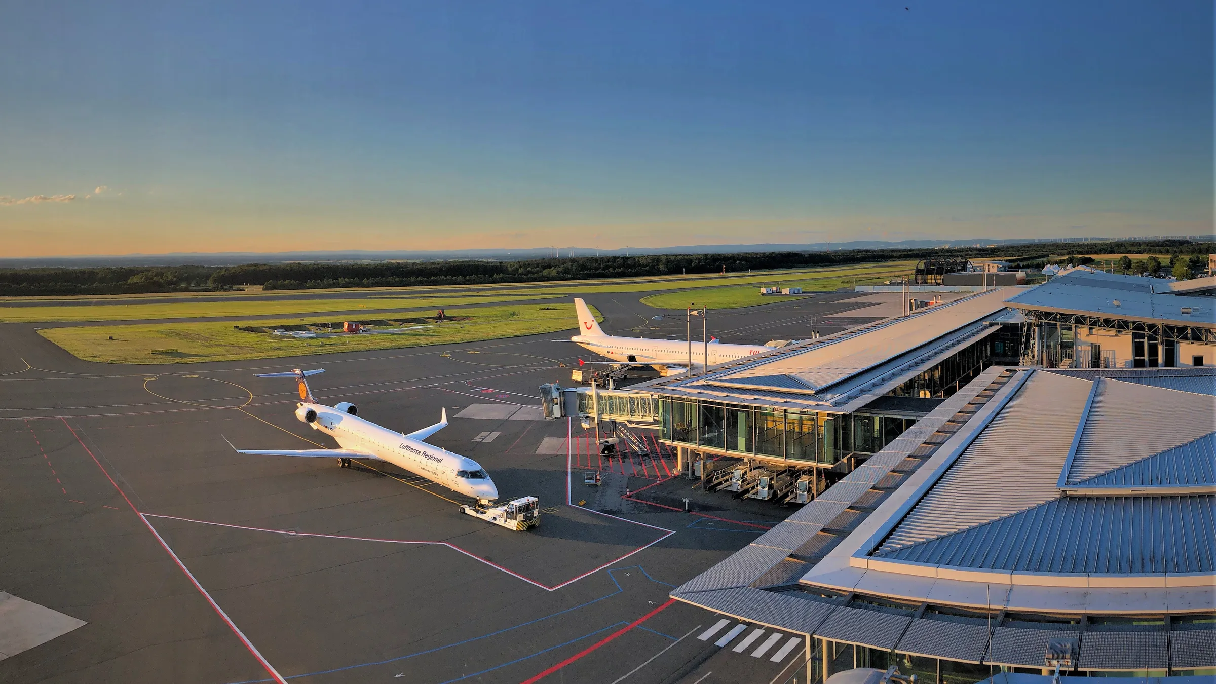 An airliner at the Paderborn/Lippstadt Airport terminal pier in low evening light