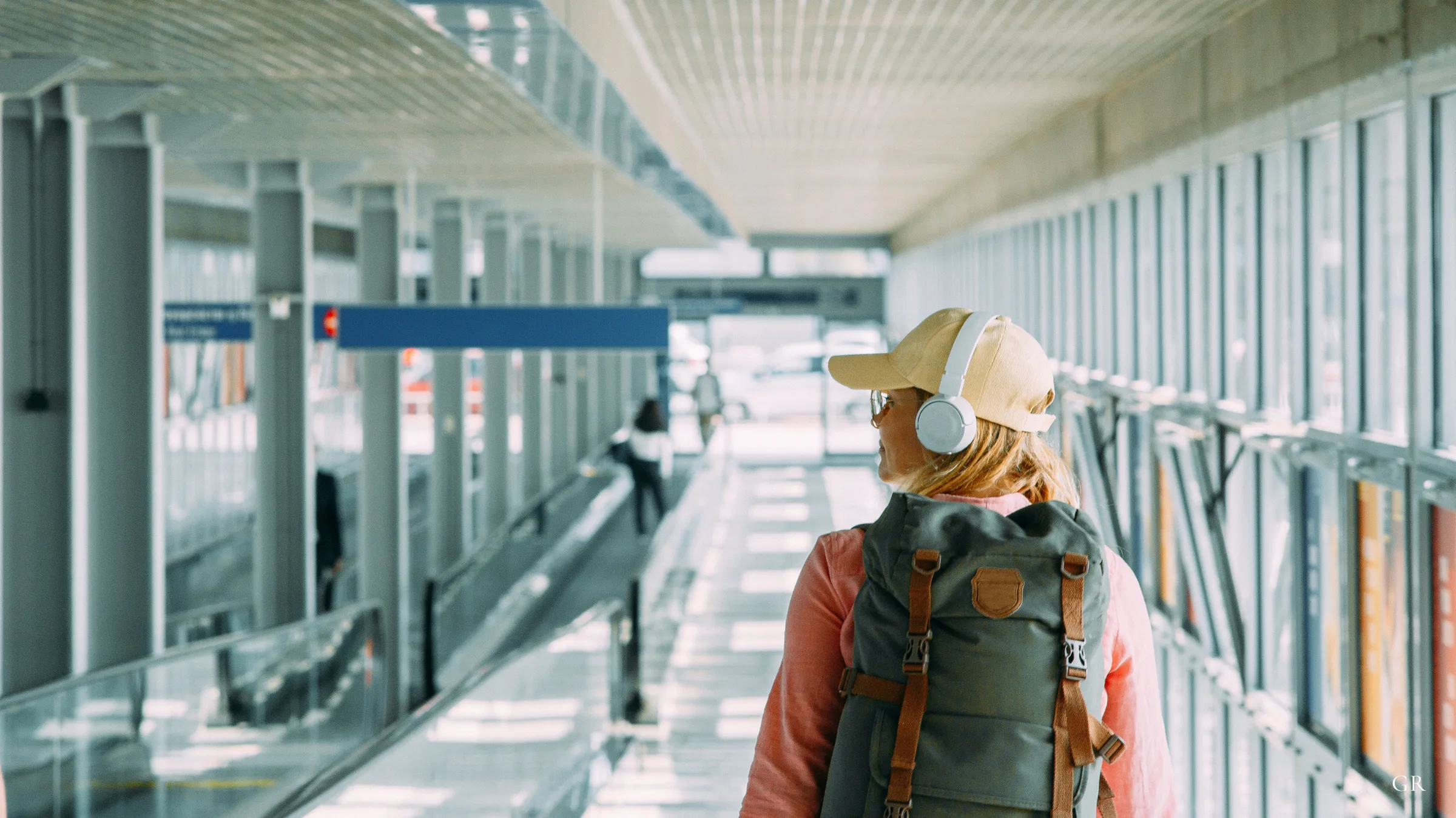 A traveller with a backpack walking an airport connecting walkway — Changing airports in Germany: what a Flughafenwechsel actually involves